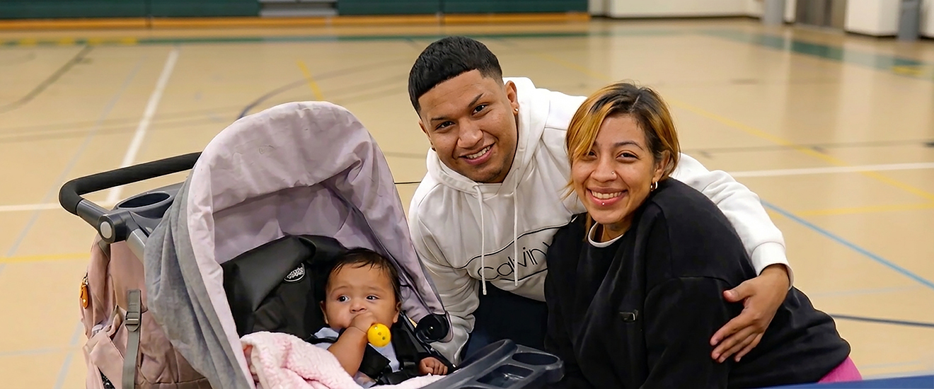 two student parents smiling their child