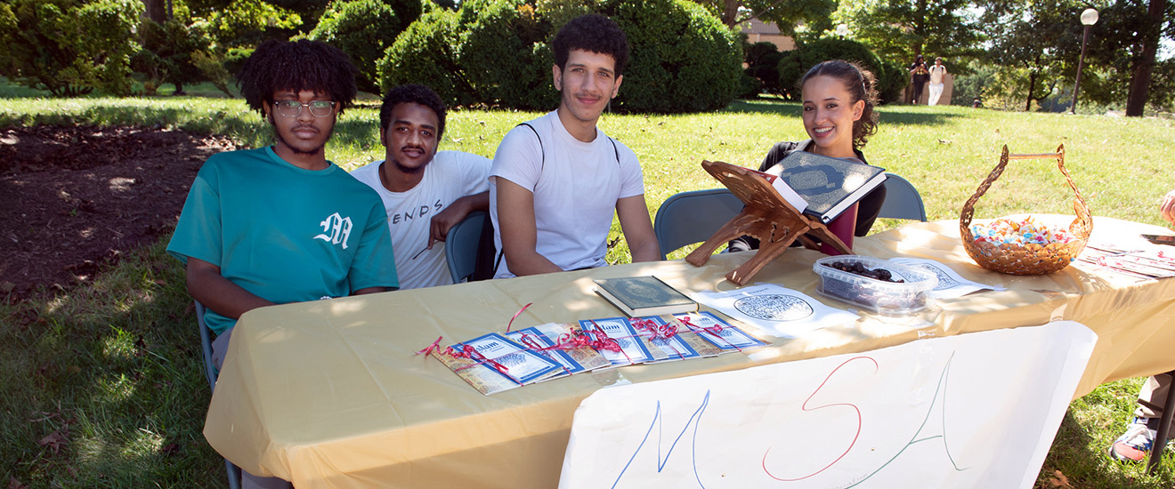 students sitting behind a club table at an event