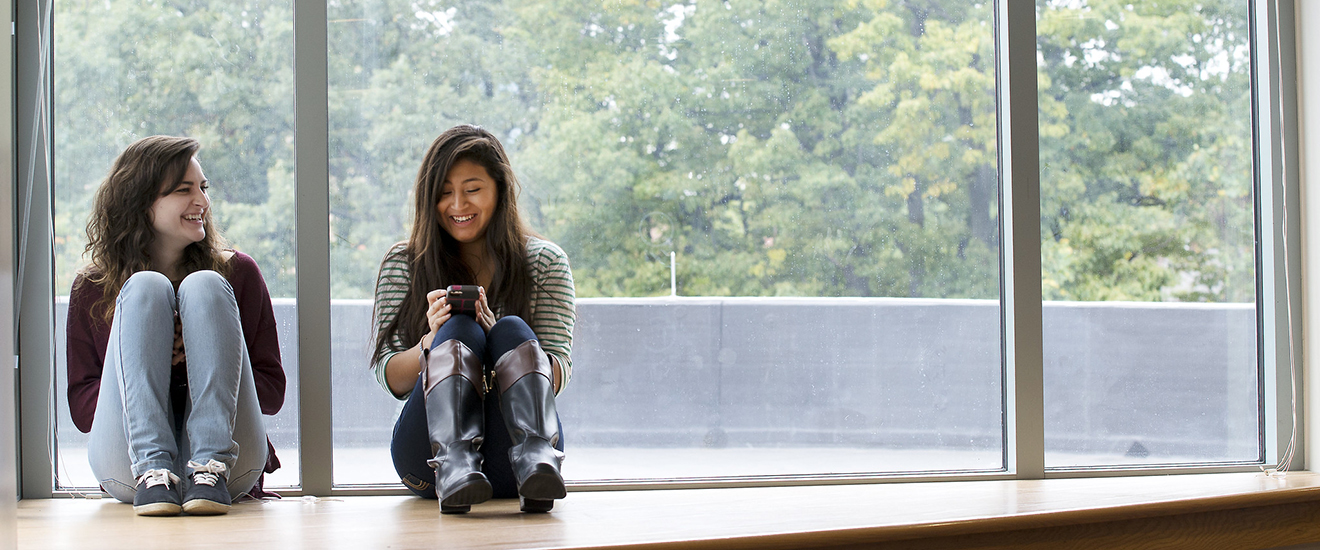 two students sitting by a window on campus