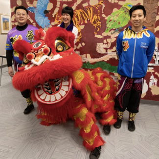 Students stand with a person dressed in a Chinese dragon costume
