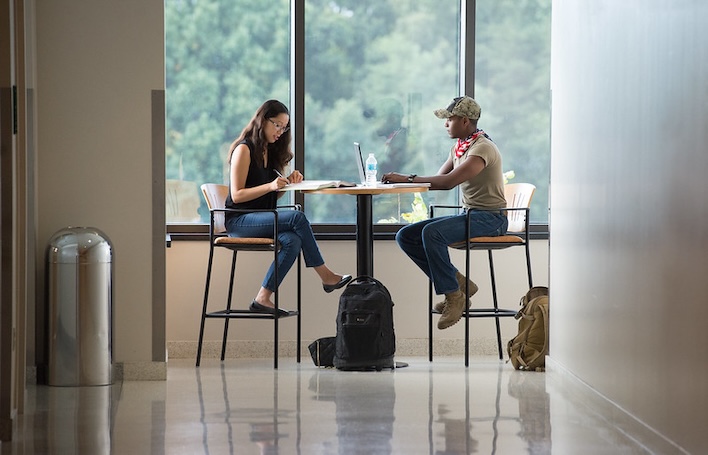 two students sitting at a table and studying