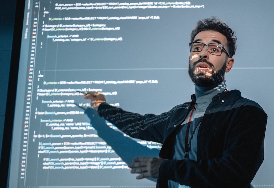 A professor pointing to information on a projection