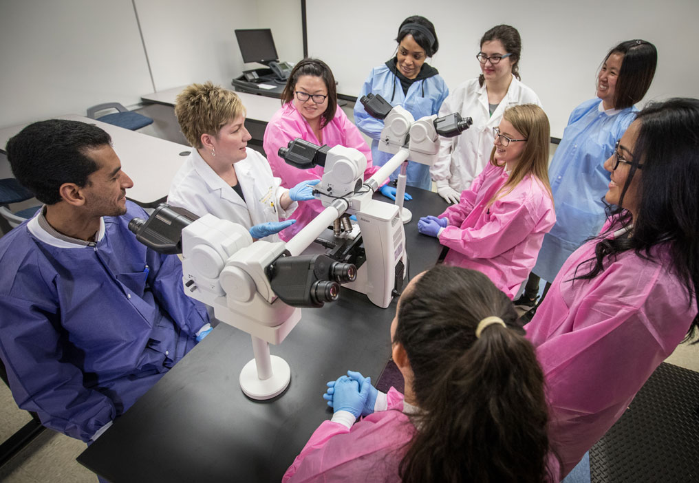 Medical Laboratory Students and instructor standing around some lab equipment