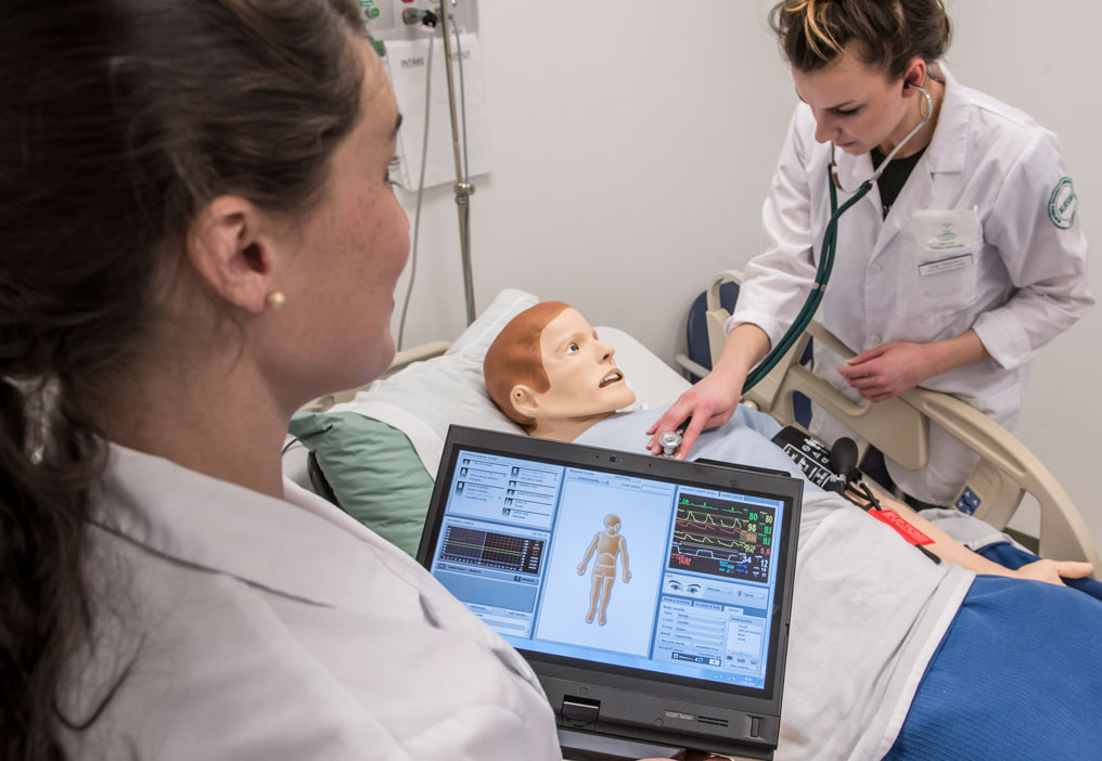 Nursing Students working with a Patient Simulation Manikin to check for vital signs