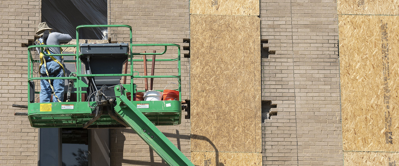 student standing on construction equipment next to a building