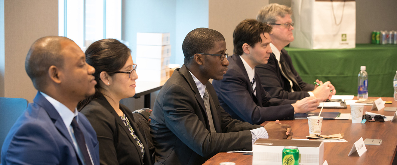 students wearing suits sitting at a conference table