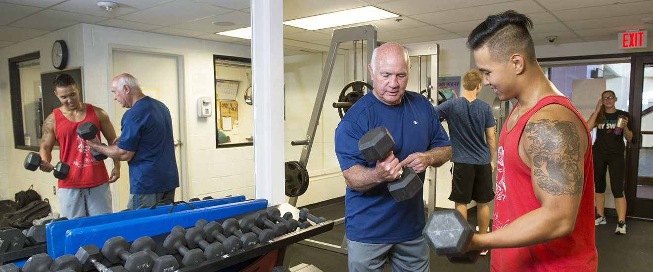A student works with an instructor in a gym setting