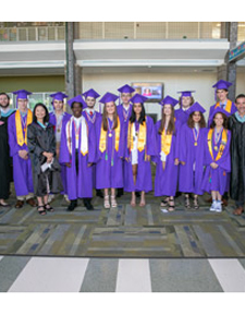 Group in purple graduation regalia with yellow graduation stoles.