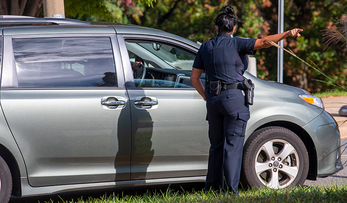 Campus police officer speaking with a driver during a traffic stop.