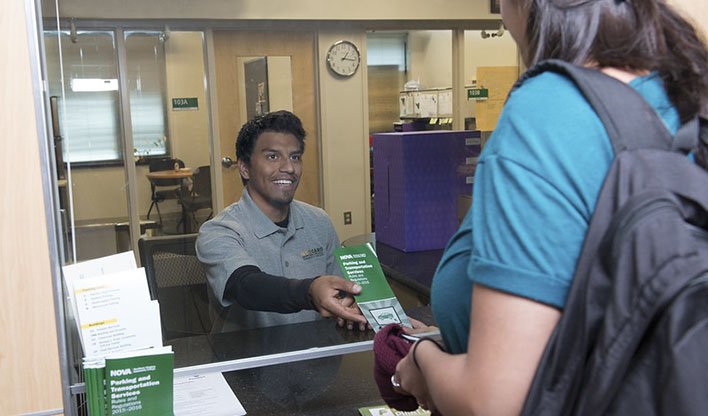 A student receiving a brochure from a staff member